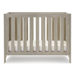 Obaby Nika Cot Bed (Grey Wash) - side view, shown here with the cot`s mattress base at its lowest level (mattress not included, available separately)