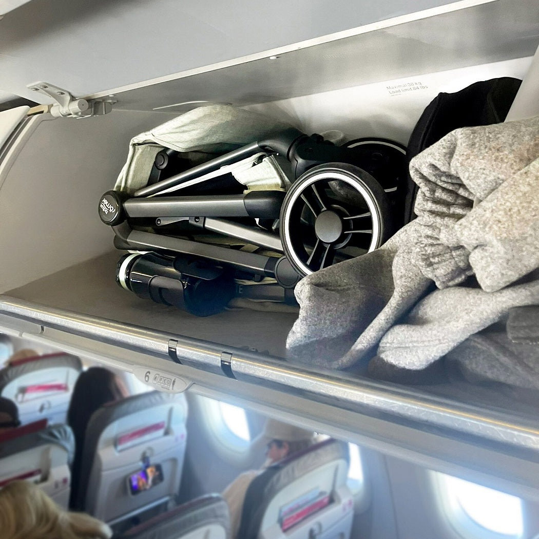 Britax Flylite Travel Stroller - Sage Green - lifestyle image, shown in an aircraft`s overhead locker