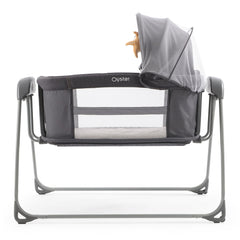 BabyStyle Oyster Swinging Crib (Fossil) - side view, showing the crib`s mesh ventilation/viewing panels