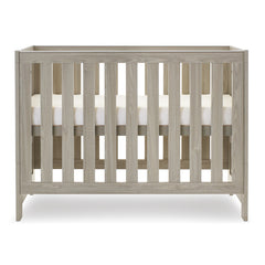 Obaby Nika Mini Cot Bed (Grey Wash) - side view, shown here with the mattress base at its highest level (mattress not included, available separately)