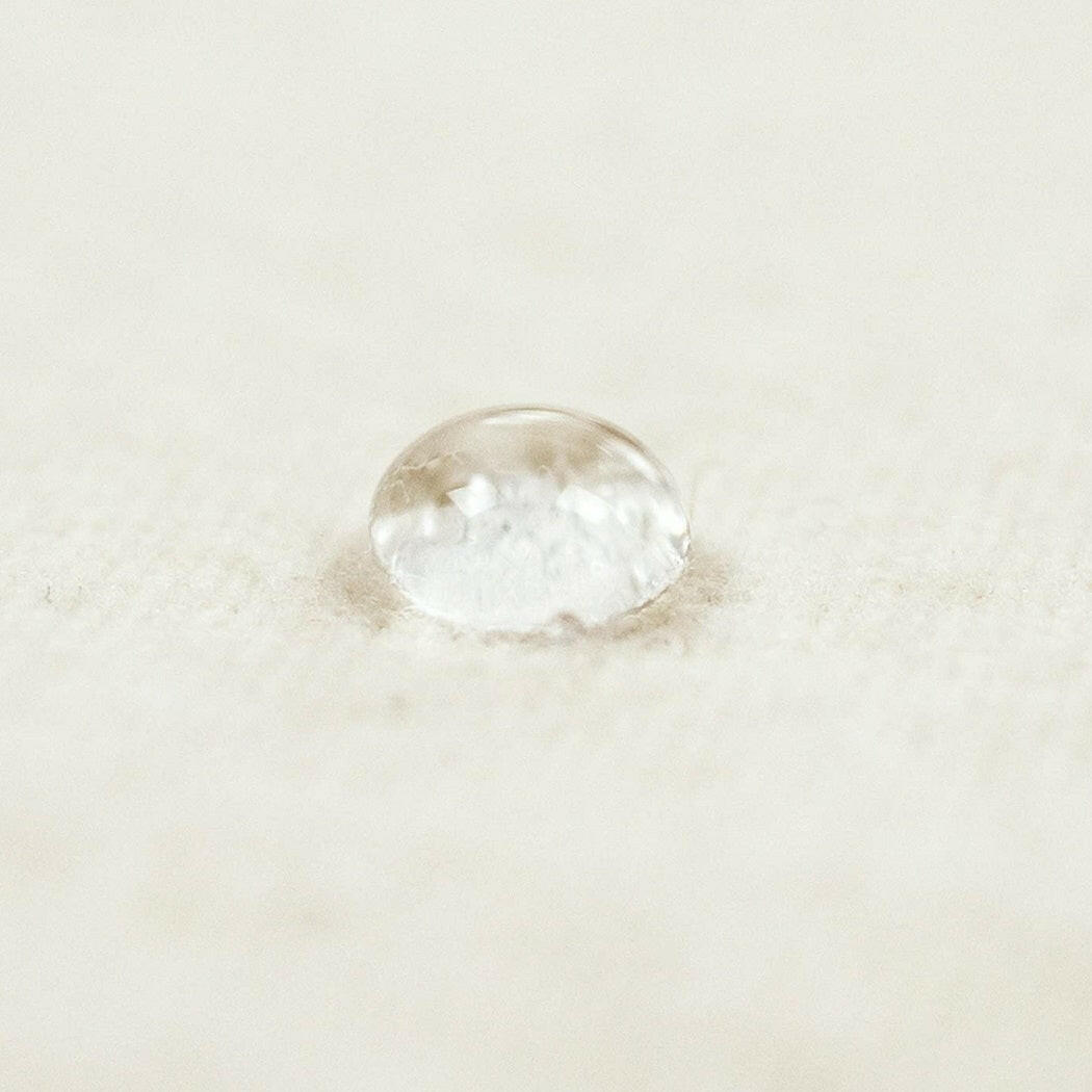 SnuzPod2 Waterproof Crib Mattress Protector - showing water sitting on top of the protector